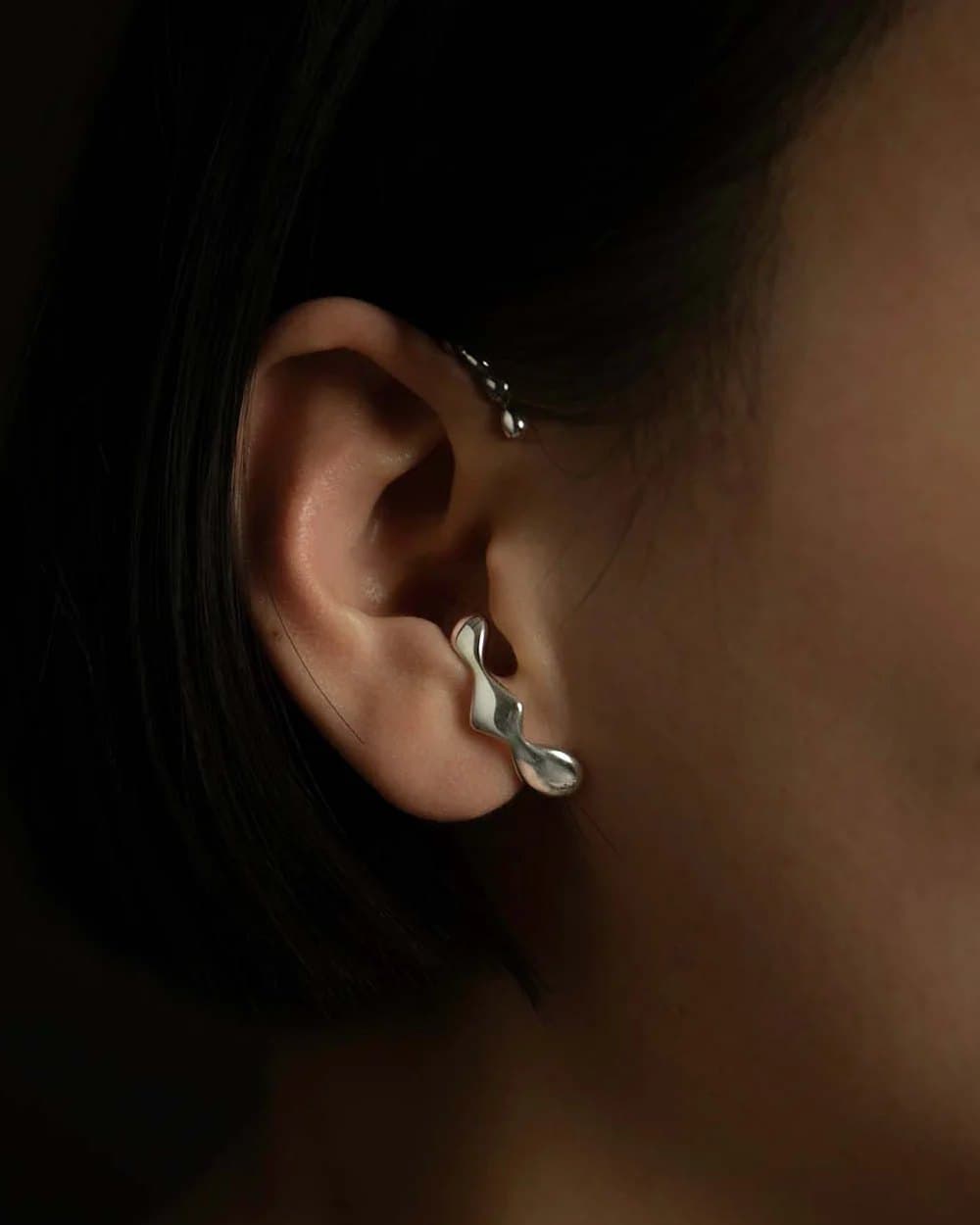 An architectural silver ear cuff resting on the cartilage, by Mara Paris