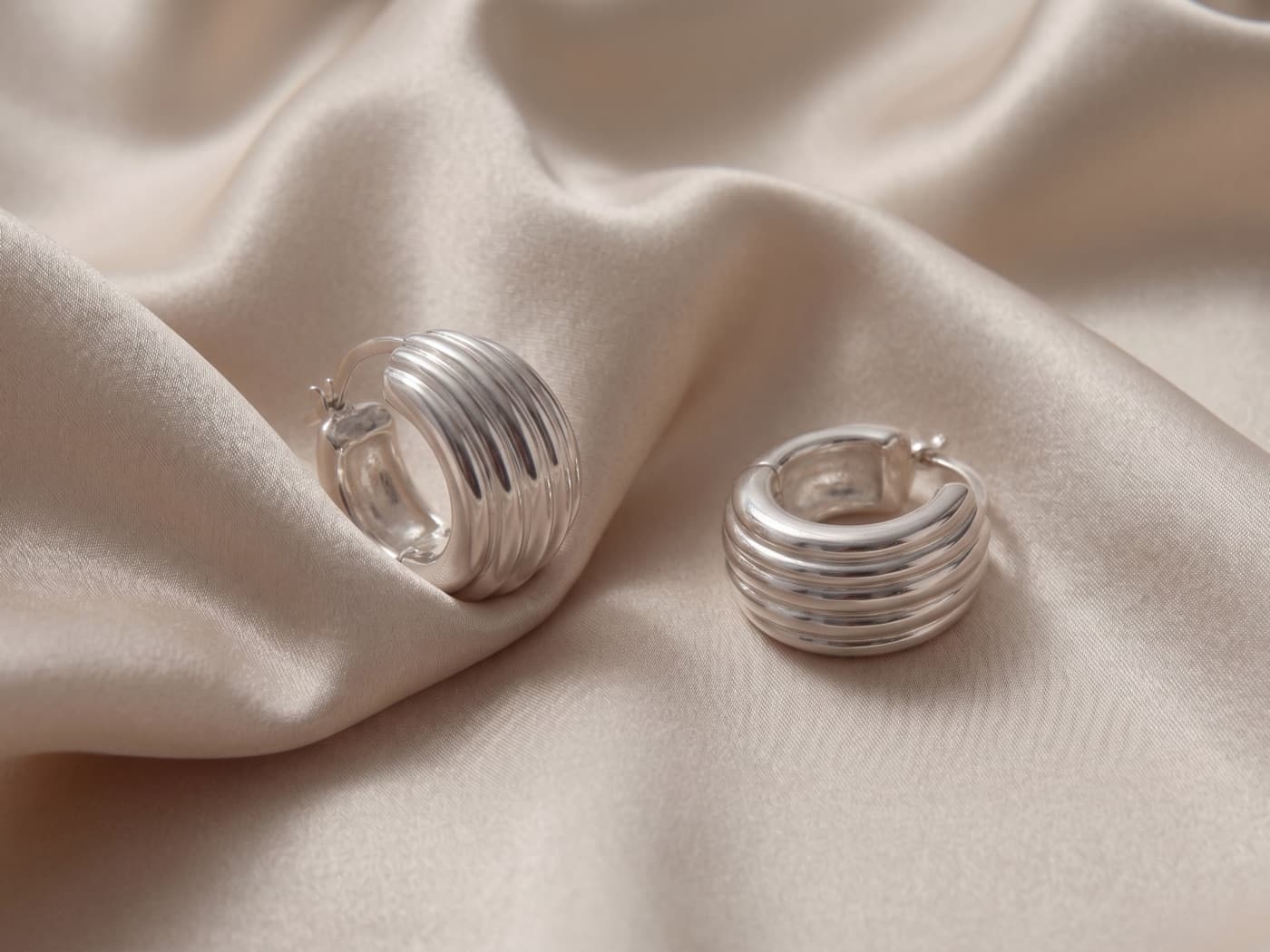 Ribbed rhodium-finished 925 sterling silver hoop earrings on champagne satin